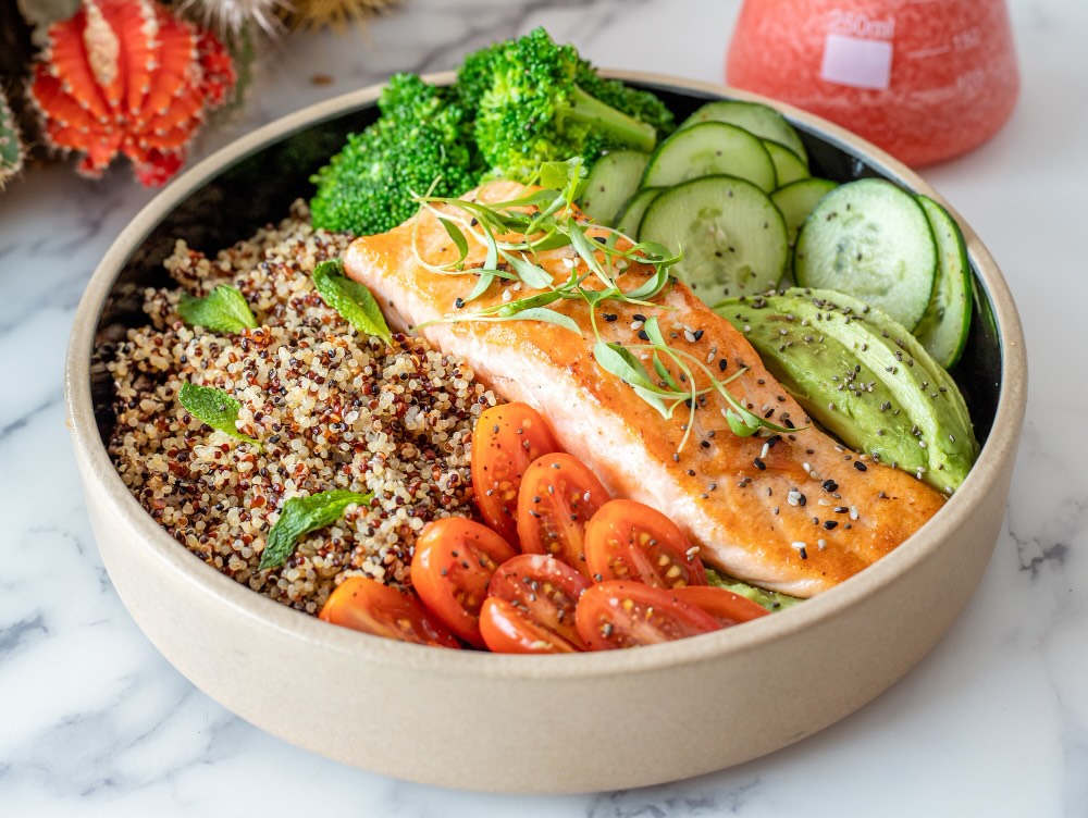 Balanced plate of clean food with salmon tomatoes, cucumbers, and quinoa.