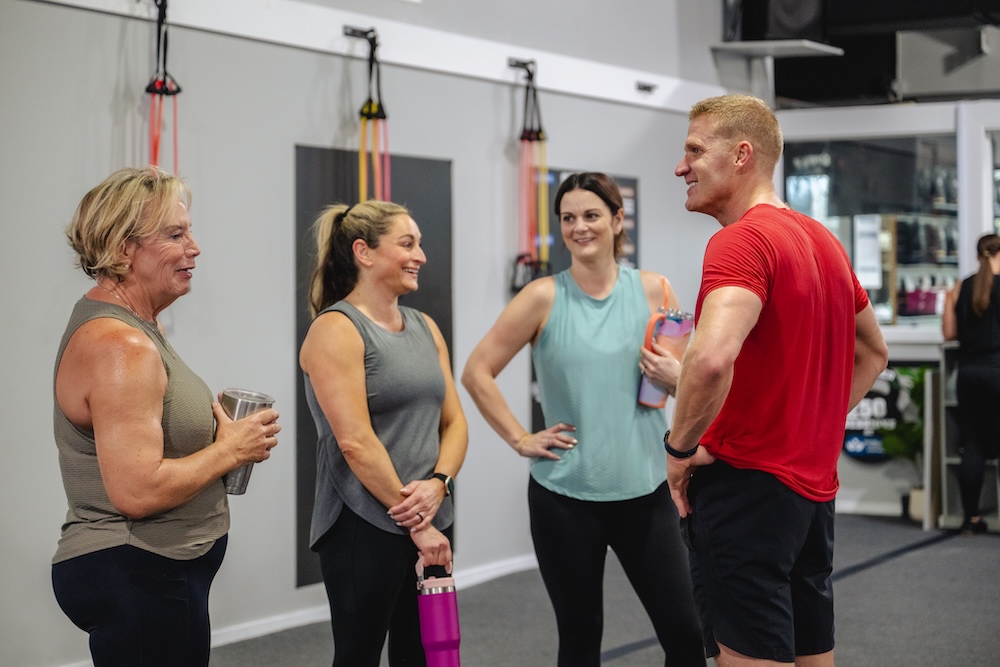 A group of people talking in their local Fit Body Boot Camp after a workout.