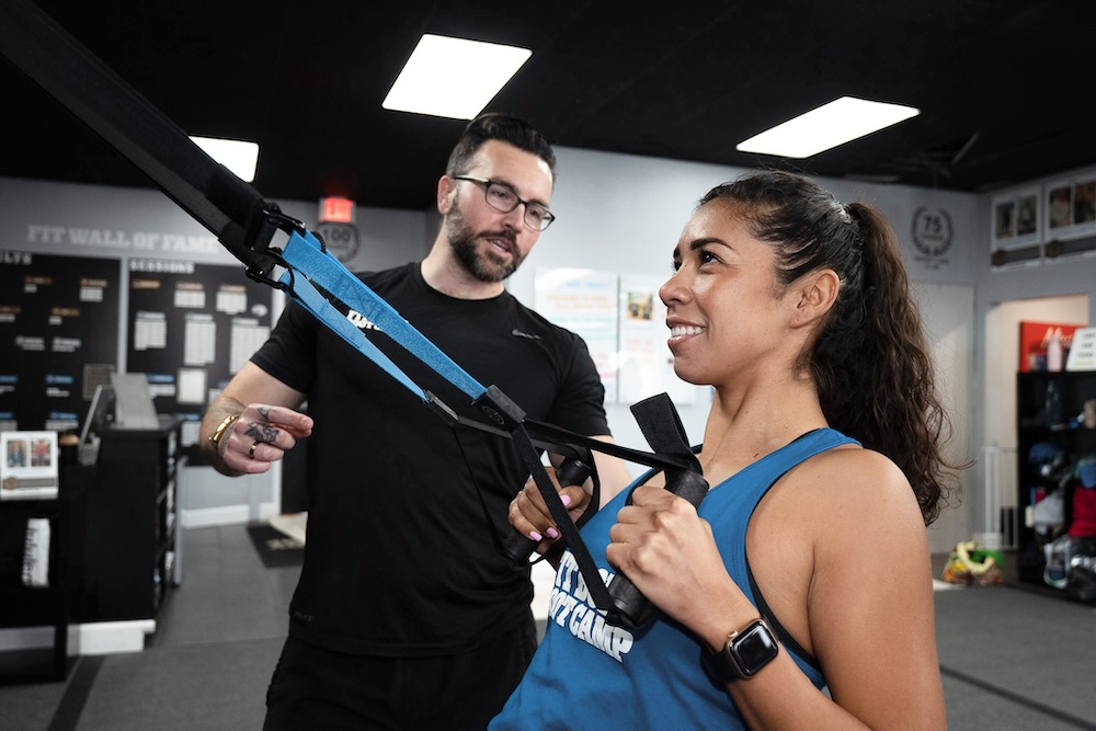 Fitness coach helping a Fit Body Boot Camp member adjust her form.