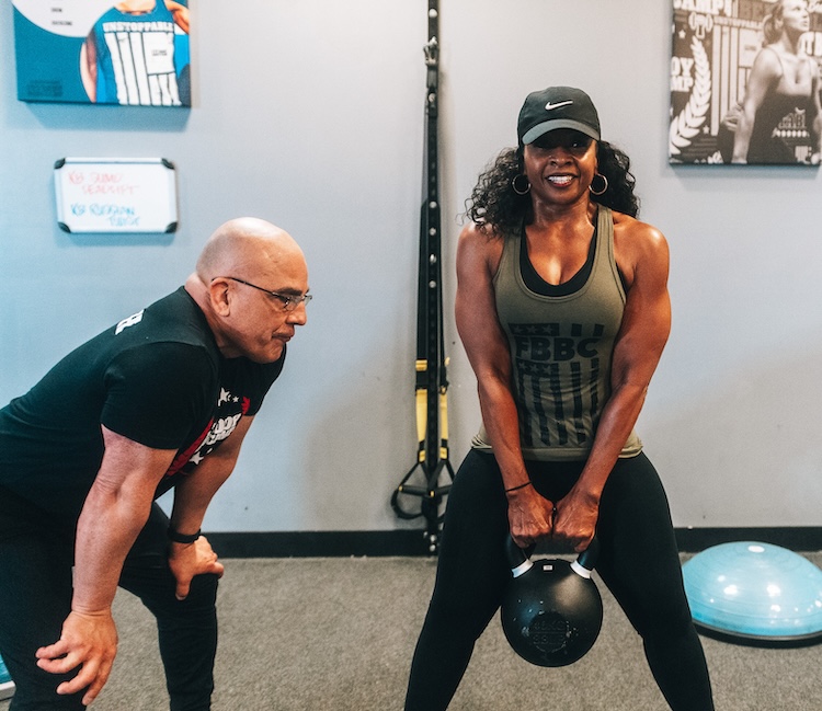 Strong woman training with kettle ball and coach